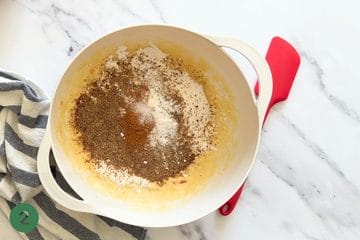 Adding the dry ingredients into the bowl of wet ingredients to make healthy applesauce cake.