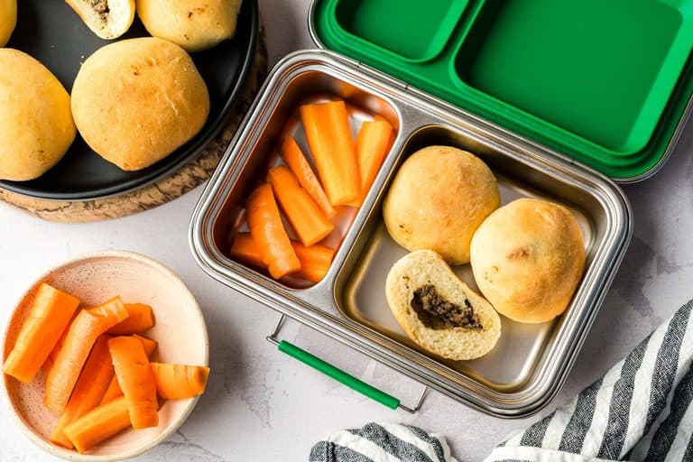 Three Mennonite meat buns in a lunchbox with cut carrots.