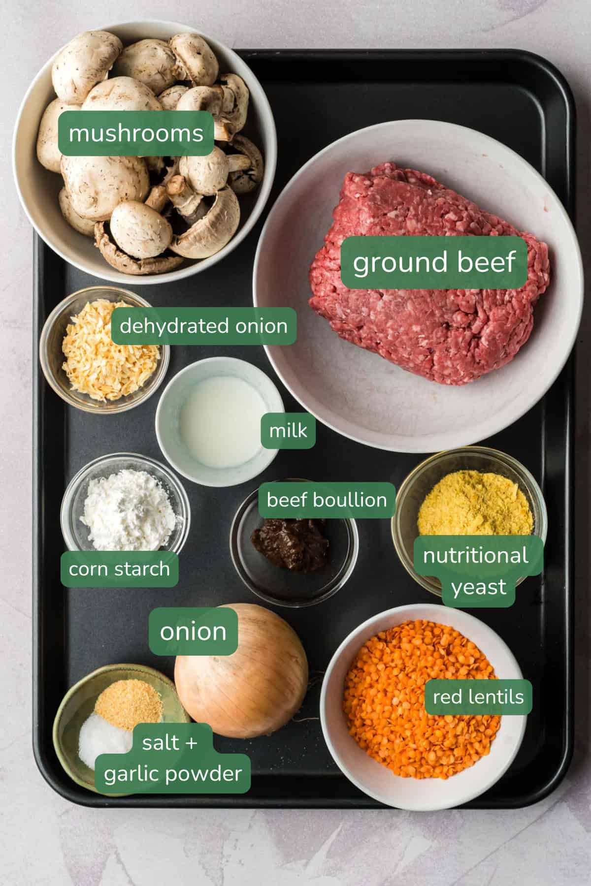 Flat lay of ingredients for meat bun filling: ground beed, red lentils, mushroom, onion, nutritional yeast, beef boullion, dehydrated chopped onion.