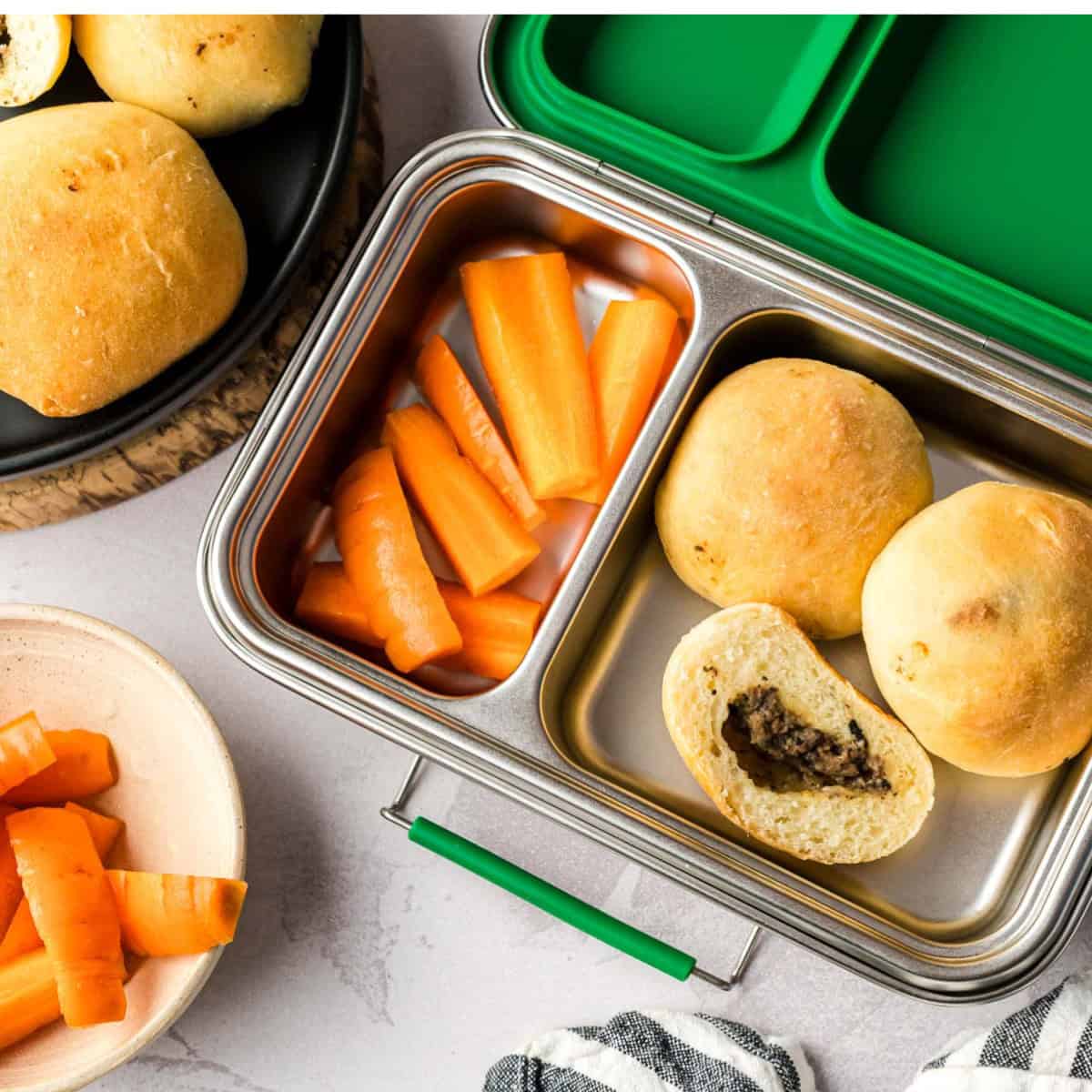 Children's lunch box filled with carrot sticks and Mennonite meat buns.