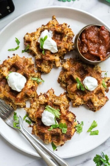 4 Savory and delicious chicken taco waffles on a plate that are garnished with cilantro.