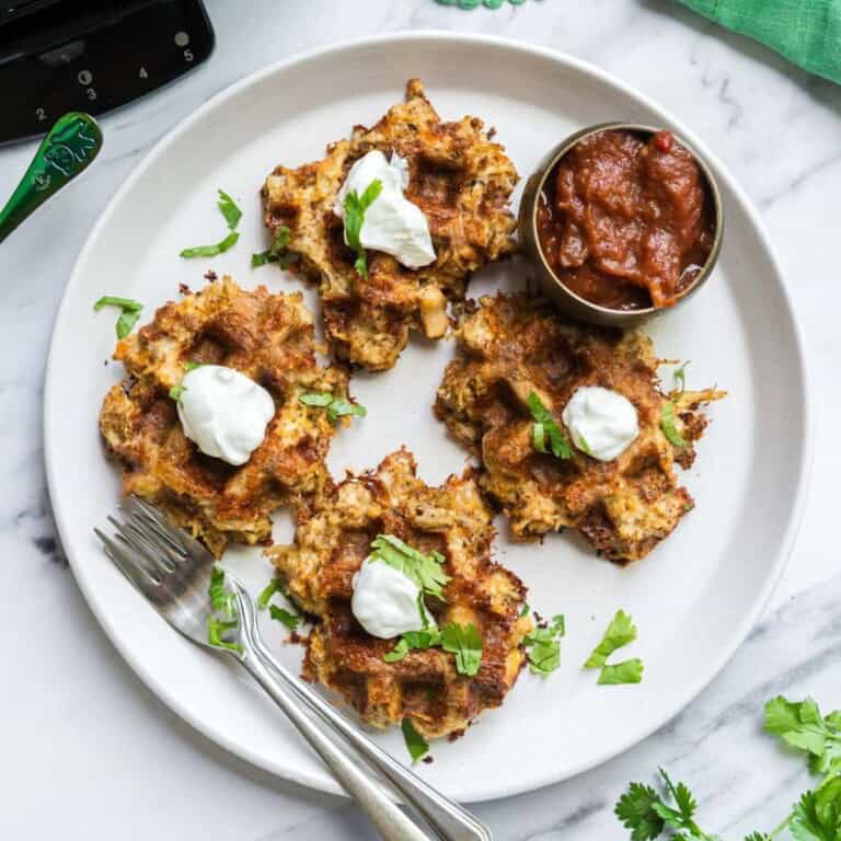 4 Savory and delicious chicken taco waffles on a plate that are garnished with cilantro.