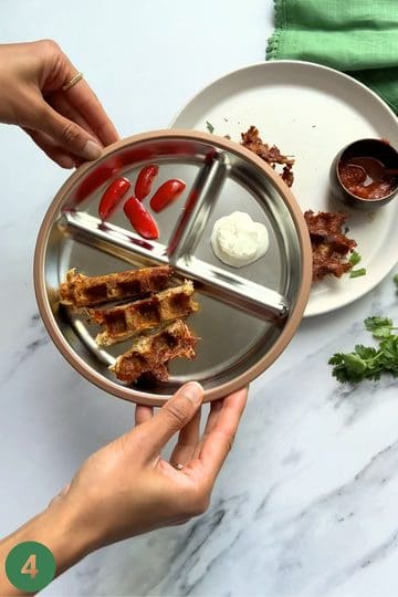 Taco chicken waffles cut into finger size slices placed in a divided plate with sour cream for dipping and cherry tomatoes quartered.